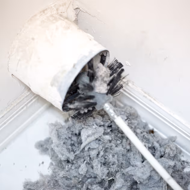 Rotary cleaning brush pulling a thick mass of lint out of a wall dryer vent pipe