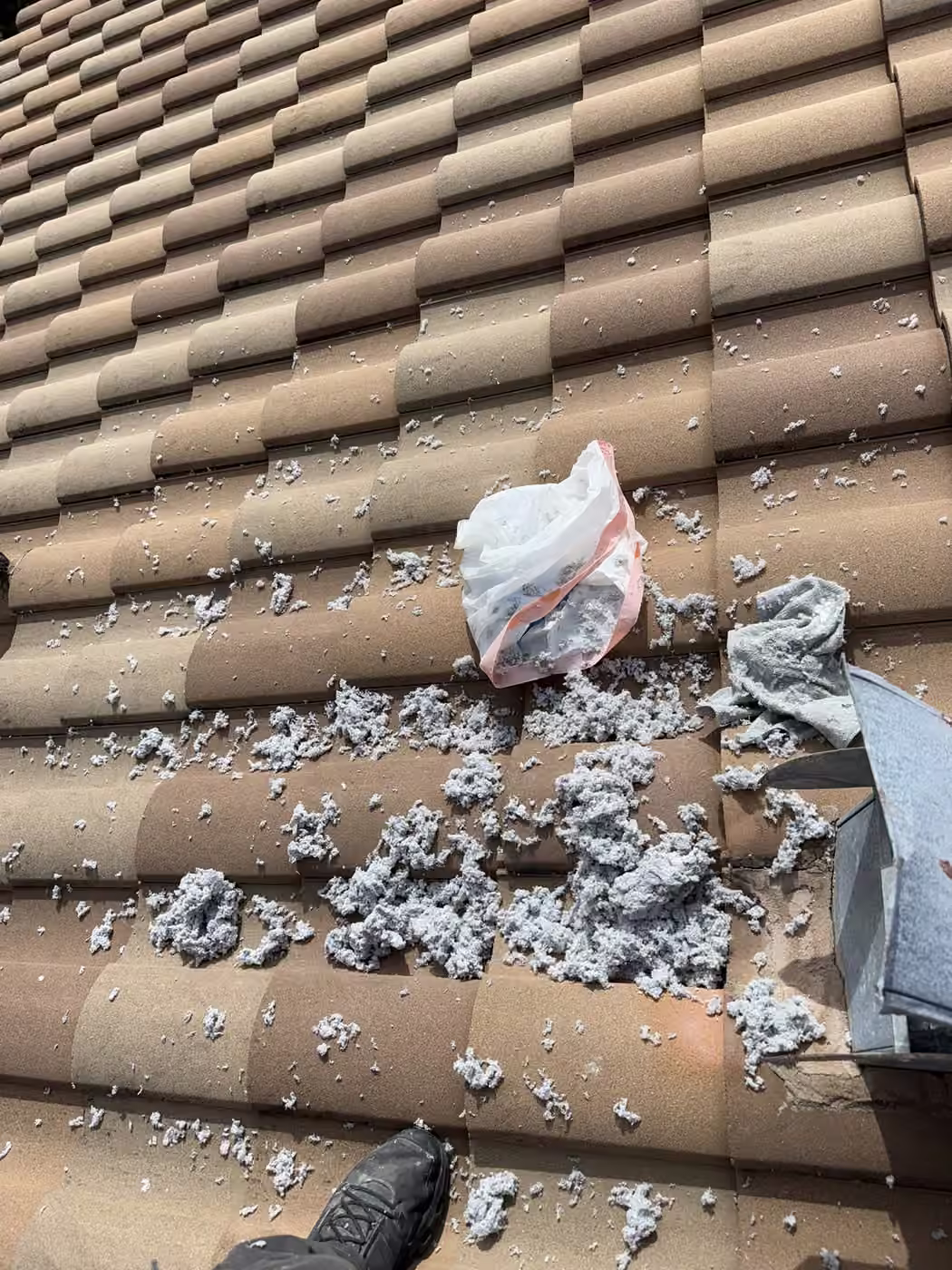 Lint cleared from a roof-terminated dryer vent beside its hood on a barrel tile roof in South Florida