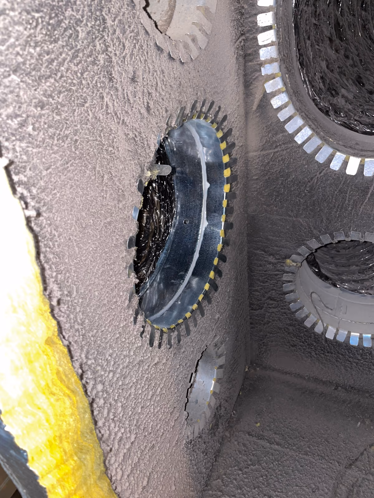 Inside a home supply plenum, showing the insulated duct takeoffs and dust coating the interior walls