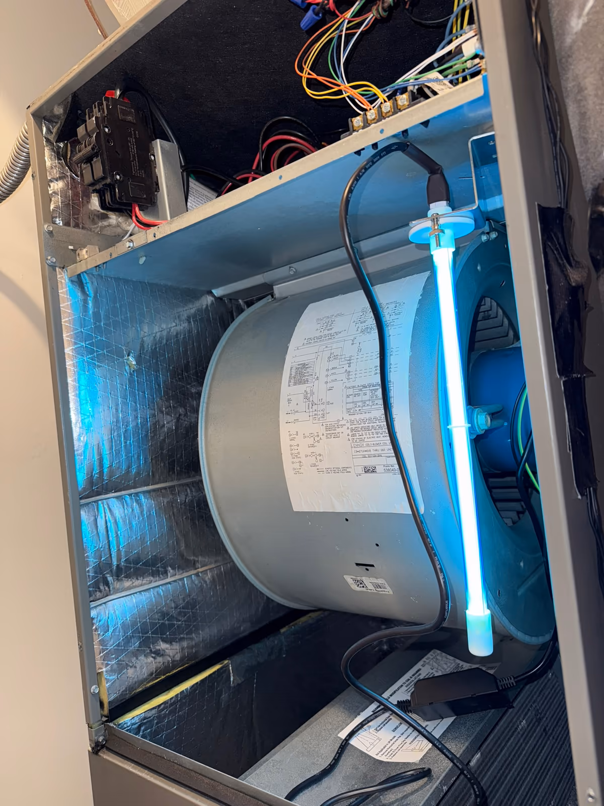 UV-C lamp mounted vertically beside the blower wheel inside an air handler